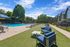 Luxurious apartment complex with a sparkling outdoor pool, surrounded by lush greenery and comfortable lounge seating under a bright blue sky.