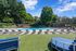 Inviting outdoor swimming pool with stylish lounge chairs and lush green surroundings under a bright blue sky.