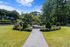 Serene garden pathway leading to a lush community park with vibrant greenery and a charming stone seating area.