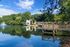 Stunning lakeside view with a modern building surrounded by lush greenery, reflecting beautifully on the serene water.