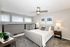 Bright, modern bedroom with elegant decor, featuring a cozy bed, stylish ceiling fan, and large windows for natural light.