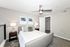 Elegant bedroom featuring a cozy bed, modern ceiling fan, and stylish decor with abstract art.