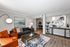 Elegant living room with stylish decor, featuring plush orange chairs, a sleek gray sofa, a chic coffee table, and contemporary artwork, creating a warm and inviting atmosphere.