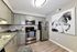 Modern kitchen with sleek stainless steel appliances, elegant grey cabinetry, and a striking monochrome horse painting enhancing the sophisticated atmosphere.