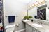 Bright and modern bathroom with a granite countertop, elegant lighting, and vibrant floral shower curtain adding a touch of color.
