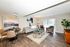 Modern living and dining area with stylish decor, featuring a cozy sofa, elegant armchairs, and a chic dining set on rich wooden flooring.