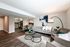 Contemporary living room with elegant decor, featuring a cozy gray sofa, stylish armchairs, and a chic dining area next to a modern kitchen.