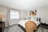 Elegant bedroom with a plush carpet, stylish artwork, and a cozy bed draped in a warm blanket, inviting relaxation.