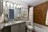 Elegant and modern bathroom with granite countertop, stylish lighting, and a chic shower area featuring designer tiles.