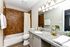 Elegant bathroom featuring granite countertops, warm brown tile walls, and stylish lighting fixtures.