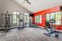 Bright and modern fitness center with state-of-the-art equipment, large windows offering natural light, and vibrant red accent wall.