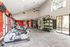 Modern fitness center with sleek exercise equipment, vibrant red accents, and spacious workout area featuring cardio machines and strength training station.
