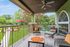 Charming covered patio with cozy seating, overlooking vibrant garden and serene pond, perfect for relaxation.