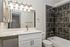 Elegant bathroom with modern fixtures, featuring a sleek white countertop, polished chrome faucet, and a stunning dark tiled shower area.