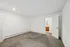 Inviting empty room with plush carpet and bright white walls, leading to an en-suite bathroom with warm wood accents.