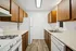 Charming galley kitchen with elegant wood cabinetry, modern appliances, and bright, inviting lighting.