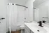 Modern and sleek bathroom featuring a minimalist design with white tiles, elegant fixtures, and a spacious vanity mirror.