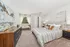 Inviting bedroom with cozy decor, plush carpet, and natural light streaming through sheer curtains. Features a comfortable bed, stylish dresser, and elegant artwork.
