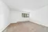 Bright and spacious room with soft carpeting, white walls, and large window offering natural light and a serene view.