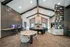 Modern communal lounge featuring high ceilings, cozy seating around a stone fireplace, stylish shelving with decorative items, and a computer workstation area.