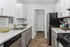 Modern kitchen with sleek white cabinetry, stainless steel appliances, and elegant wood flooring.