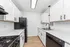 Modern kitchen featuring sleek white cabinetry, elegant black appliances, and stylish wood flooring for a fresh, contemporary look.