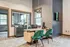 Modern office space with plush green chairs, stylish wooden desk, and large windows offering natural light and scenic views.