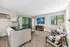 Chic living room featuring large windows, modern decor, and plush carpeting with a view of lush greenery.