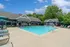 Inviting outdoor pool area with modern loungers, umbrellas, and a charming clubhouse under a vibrant blue sky.