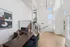 Bright modern office space with elegant wooden desk, sleek black chairs, and eye-catching abstract artwork under a stunning chandelier.