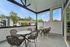 Charming outdoor balcony with stylish wicker furniture, offering idyllic views of lush trees and modern neighboring apartments.