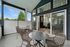 Charming modern patio with elegant wicker seating overlooking lush greenery, seamlessly connected to a cozy living room with large windows and a fireplace.