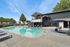 Inviting outdoor pool area with modern lounge chairs, sleek umbrellas, and a charming clubhouse backdrop under a clear blue sky.