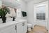 Bright modern bathroom featuring elegant white cabinetry, sleek fixtures, and stylish plant decor, offering a serene ambiance.