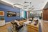 Contemporary lounge area featuring luxurious leather sofas, elegant circular chandeliers, and modern art on a stylish blue accent wall.
