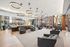 Modern lounge area with chic black armchairs, stylish circular pendant lights, and floor-to-ceiling windows offering vibrant city views.