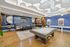 Chic game room featuring modern pool table, stylish seating, and vibrant blue walls with contemporary decor.