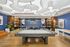 Chic and contemporary game room with stylish decor, featuring a pool table, modern workspaces, and vibrant blue accents.