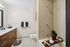 Modern bathroom featuring sleek wooden cabinetry, dual sinks, and a relaxing bathtub with elegant decor.