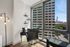 Bright corner office space with large windows offering stunning city views, modern black desk, and elegant lighting.