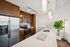 Modern kitchen with elegant dark wood cabinets, sleek stainless steel appliances, and a bright, stylish countertop accented by a chic pendant light and lush greenery.