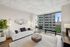 Modern living room with chic white sofa, floor-to-ceiling windows, and stunning city views.