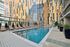 Luxurious outdoor pool area with modern lounge chairs and vibrant cityscape reflections, perfect for relaxation and leisure.