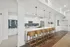 Elegant modern kitchen with sleek white cabinets, a stunning blue tile backsplash, and a spacious island with wooden barstools and pendant lighting.