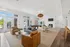 Luxurious open-concept living space with elegant seating, a pool table, and a cozy fireplace, bathed in natural light from expansive windows.