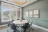Elegant meeting room with a round table surrounded by modern chairs, featuring large windows and stylish artwork on a green wall.