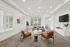 Elegant living room with stylish leather chairs, modern sofa, and decorative accent pieces, bathed in natural light from large windows.