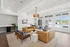 Elegant and spacious living room with large windows offering a bright, airy feel, stylish seating, and a cozy work nook.