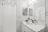 Bright, modern bathroom with sleek white countertops, elegant fixtures, and a spacious shower, ideal for a refreshing start to the day.