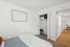 Inviting bedroom with soft, elegant decor, featuring a cozy bed, spacious closet, and a glimpse into a hallway with warm wooden flooring.